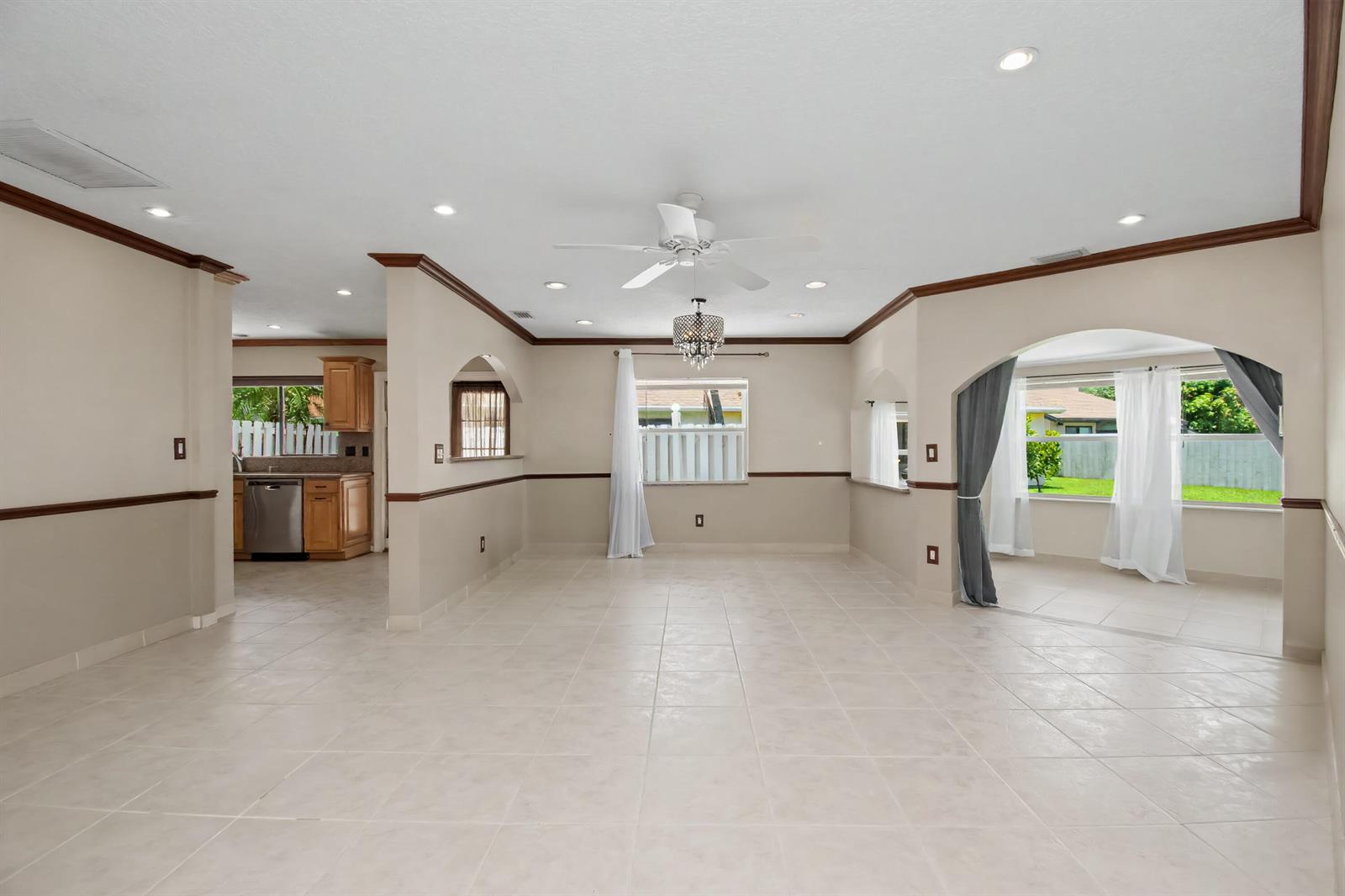 An open-concept living area features tile flooring, crown molding, a ceiling fan, and arched openings — 9709 Sunny Isle Circle, Boca Raton FL 33428, BOCA RATON, FL