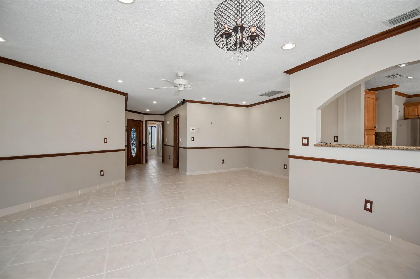 An open-concept dining area features tile flooring, crown molding, and a decorative chandelier — 9709 Sunny Isle Circle, Boca Raton FL 33428, BOCA RATON, FL
