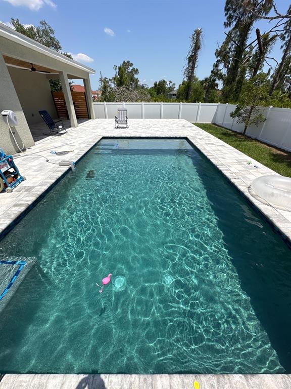 A rectangular swimming pool with a stone deck sits in a fenced backyard — 1871 BRADDOCK AVENUE, NORTH PORT, FL