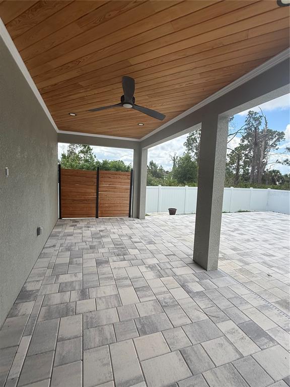 A covered patio features a wood-plank ceiling, a ceiling fan, and gray paver flooring — 1871 BRADDOCK AVENUE, NORTH PORT, FL