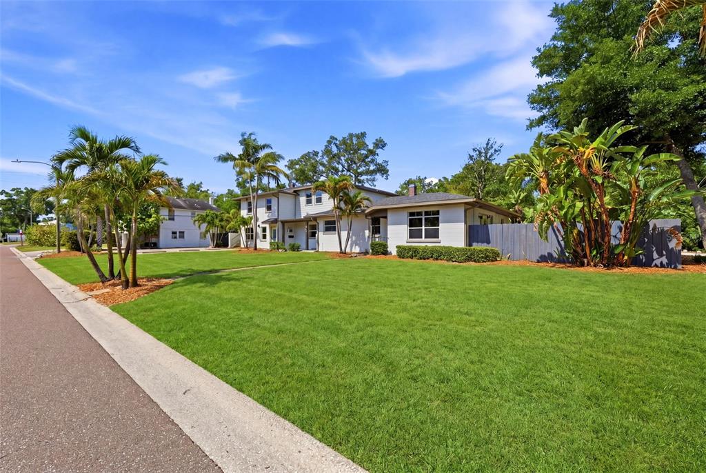 A two-story house with a large green lawn, palm trees, and a blue fence — 3030 5TH STREET N, ST PETERSBURG, FL