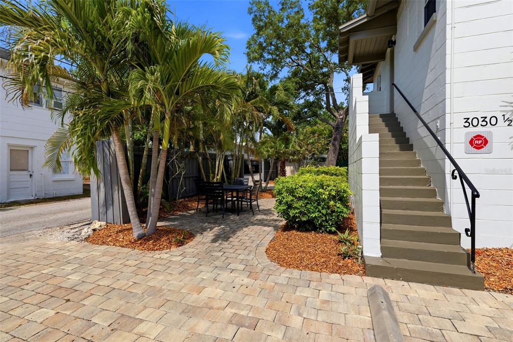 An outdoor patio area with a table and chairs sits beside a building with stairs — 3030 5TH STREET N, ST PETERSBURG, FL