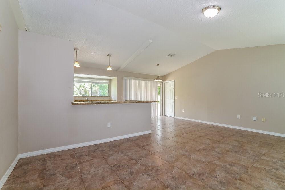 An open-concept living area features tile flooring, a breakfast bar, and a vaulted ceiling — 5343 BROKEN PINE CIRCLE, ORLANDO, FL