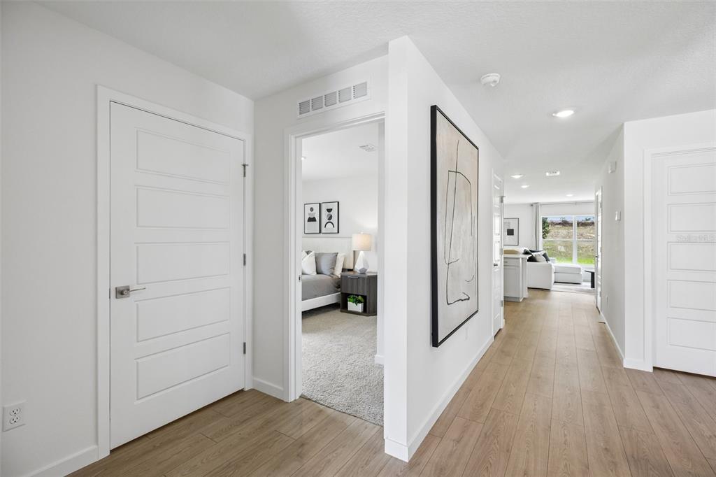 A hallway with wood-look flooring leads to a bedroom and an open living area — 239 SKYFIELD COURT, LADY LAKE, FL