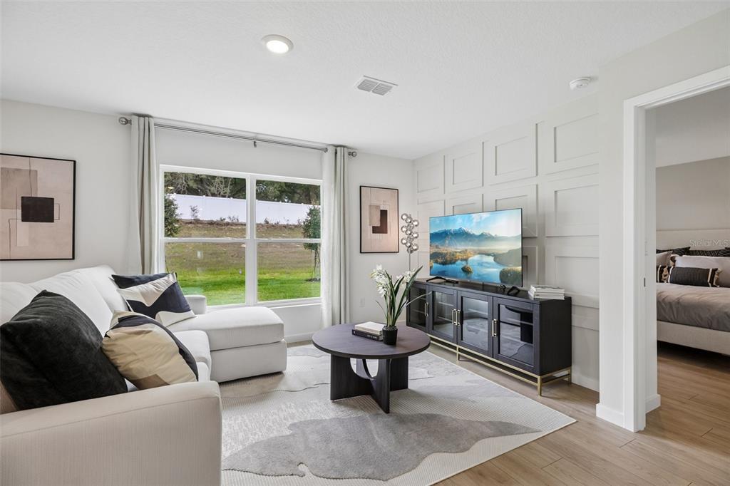 A living room features a white sectional sofa, a round coffee table, and paneled walls — 239 SKYFIELD COURT, LADY LAKE, FL