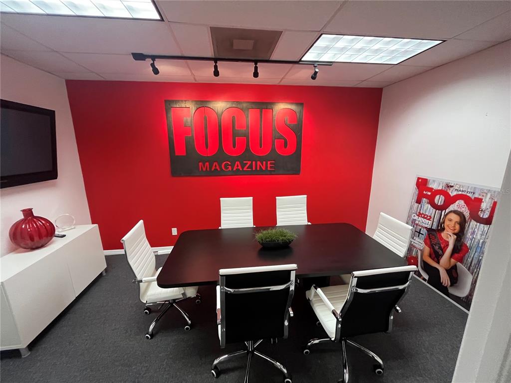 A conference room features a red accent wall with a Focus Magazine sign and furniture — 702 W DR MARTIN LUTHER KING JR BOULEVARD, PLANT CITY, FL