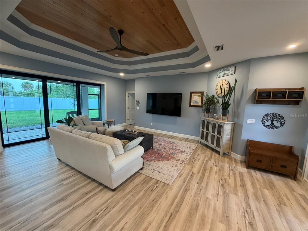 A living room features a tray ceiling with wood inlay, light blue walls, and sliding doors — 218 COUGAR WAY, ROTONDA WEST, FL