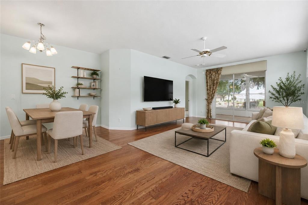 A living and dining area features hardwood floors, a television console, and a sliding glass door — 4905 KELSO STREET, LEESBURG, FL
