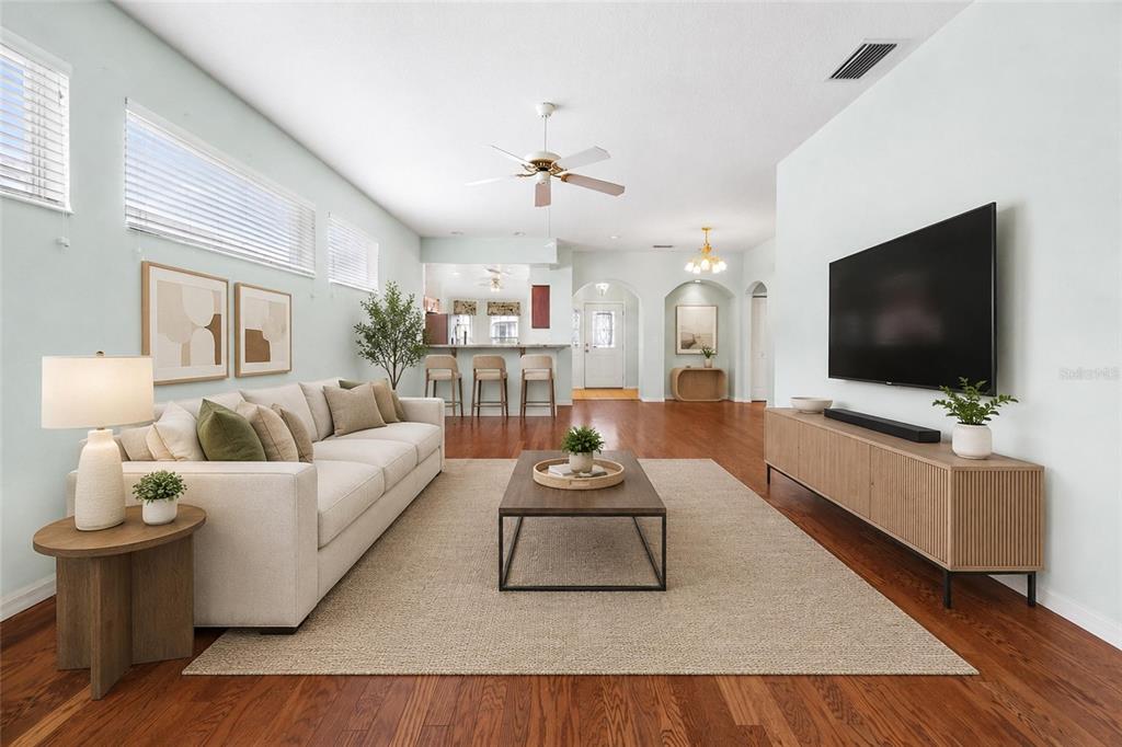 A bright living room features a beige sofa, wooden coffee table, and a wall-mounted television — 4905 KELSO STREET, LEESBURG, FL