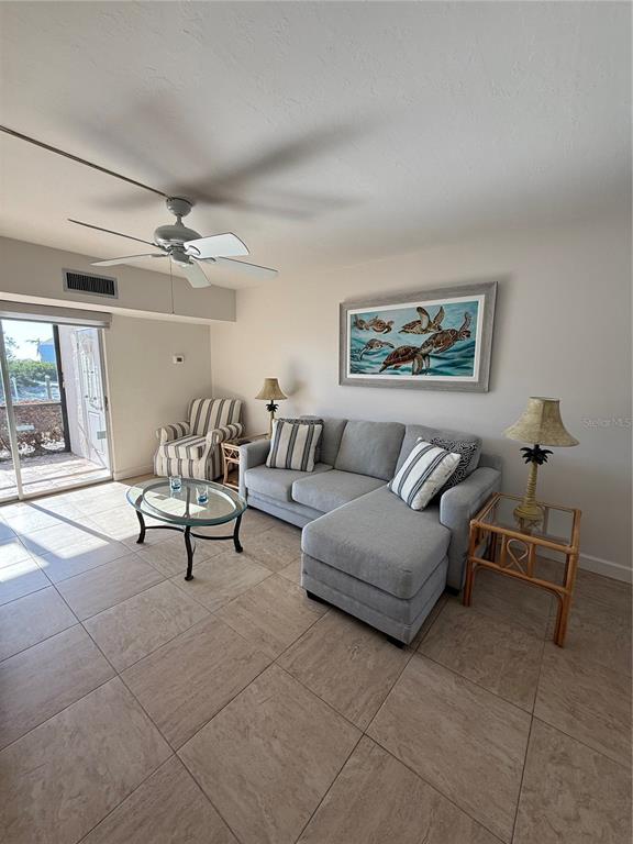 A living room features a gray sectional sofa, a glass coffee table, and tile flooring — 9200 MIDNIGHT PASS ROAD UNIT 10, SARASOTA, FL