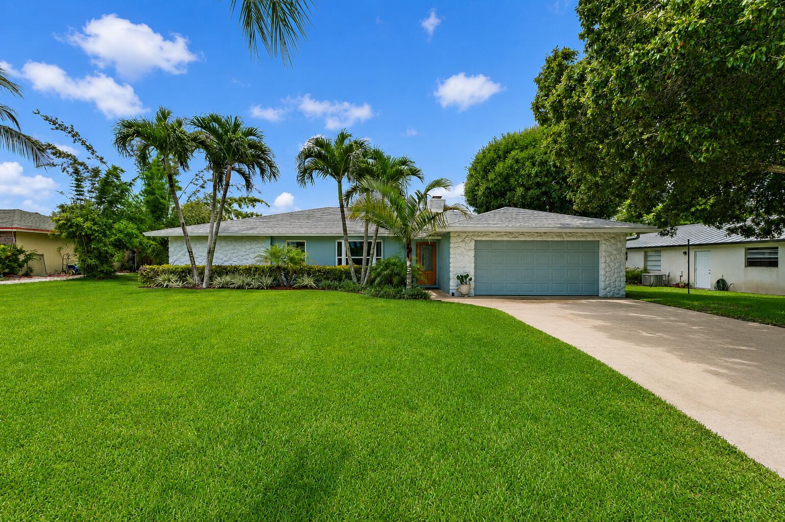 A single-story house with a light blue exterior, stone accents, and a two-car garage — 76 Wingo Street, Tequesta FL 33469, TEQUESTA, FL