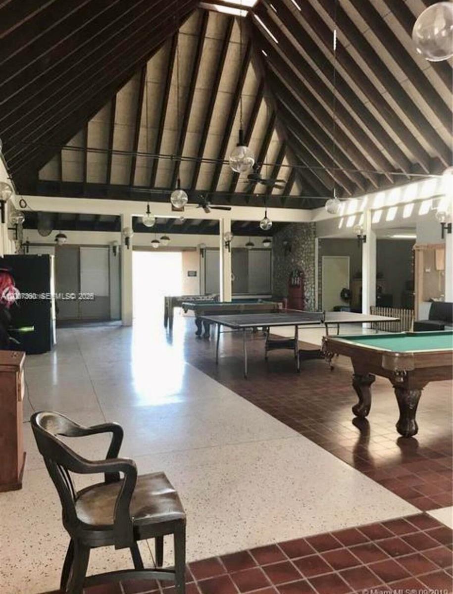 A large recreation room features a high vaulted ceiling, tile flooring, and multiple game tables — 324 Pine Cone Avenue, Clewiston FL 33440, CLEWISTON, FL