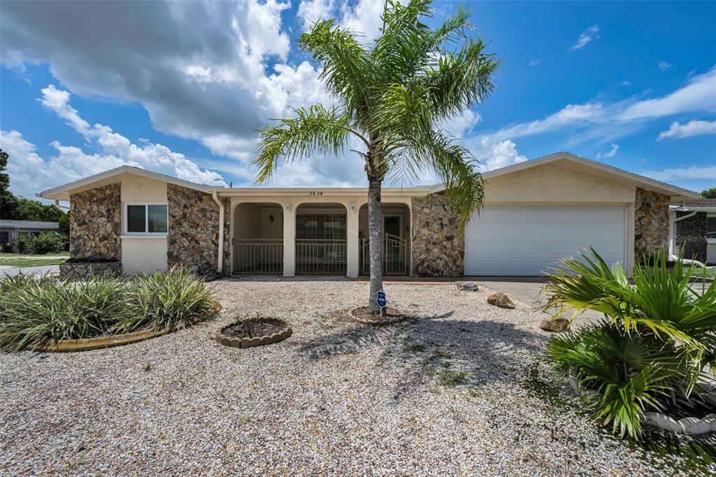 A single-story house with a stone facade, a covered porch, and a gravel front yard — 5834 EMBAY AVENUE, NEW PORT RICHEY, FL