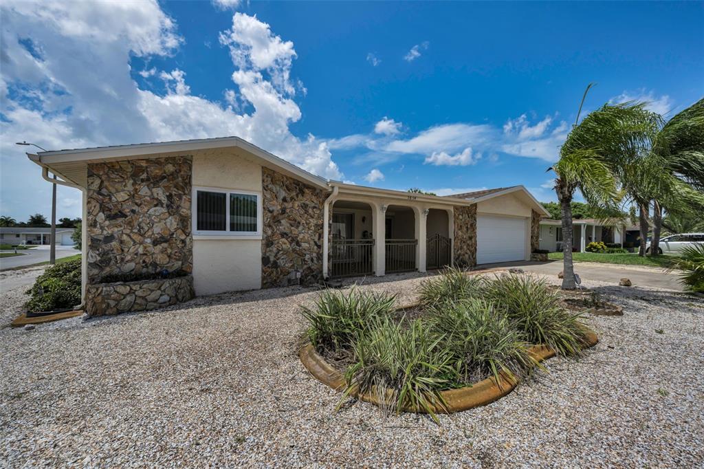 A single-story house with stone veneer siding, a gravel front yard, and a covered porch — 5834 EMBAY AVENUE, NEW PORT RICHEY, FL