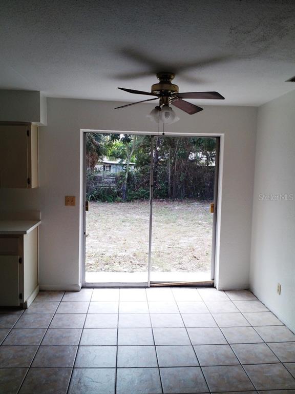 A dining area with tile flooring, a ceiling fan, and sliding glass doors to a yard — 4150 BARRACUDA DRIVE SE, ST PETERSBURG, FL