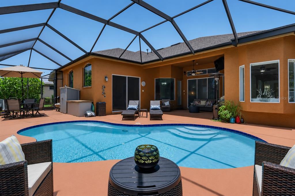 A screened-in patio features a swimming pool, lounge chairs, and outdoor furniture — 16410 IVY LAKE DRIVE, ODESSA, FL