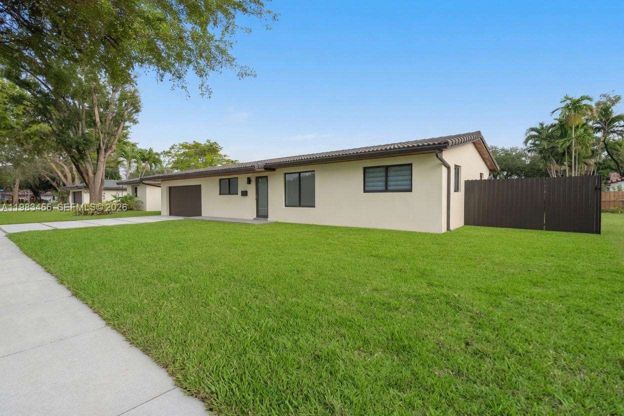 A single-story house with a beige exterior, dark roof, and a fenced side yard — 14515 Mahogany Ct, Miami Lakes FL 33014, MIAMI LAKES, FL