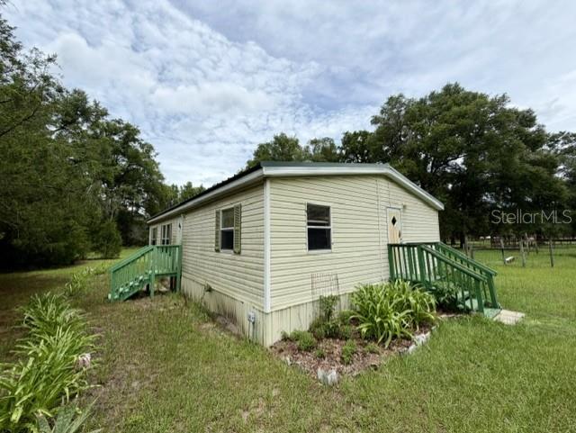 A light-colored mobile home with a metal roof and a small green wooden porch — 4760 NW 55TH AVENUE, BELL, FL
