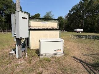 An outdoor Generac generator sits next to a utility shed and electrical equipment on a grassy lot — 4760 NW 55TH AVENUE, BELL, FL