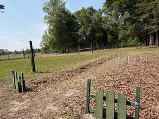 A grassy field features a dirt path, wooden fence sections, and a line of trees — 4760 NW 55TH AVENUE, BELL, FL