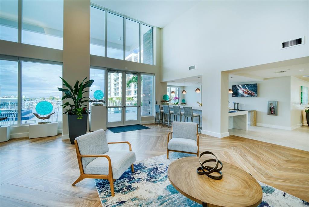 A modern lobby features floor-to-ceiling windows, a bar area, and light wood flooring — 900 N OSCEOLA AVENUE UNIT 401, CLEARWATER, FL