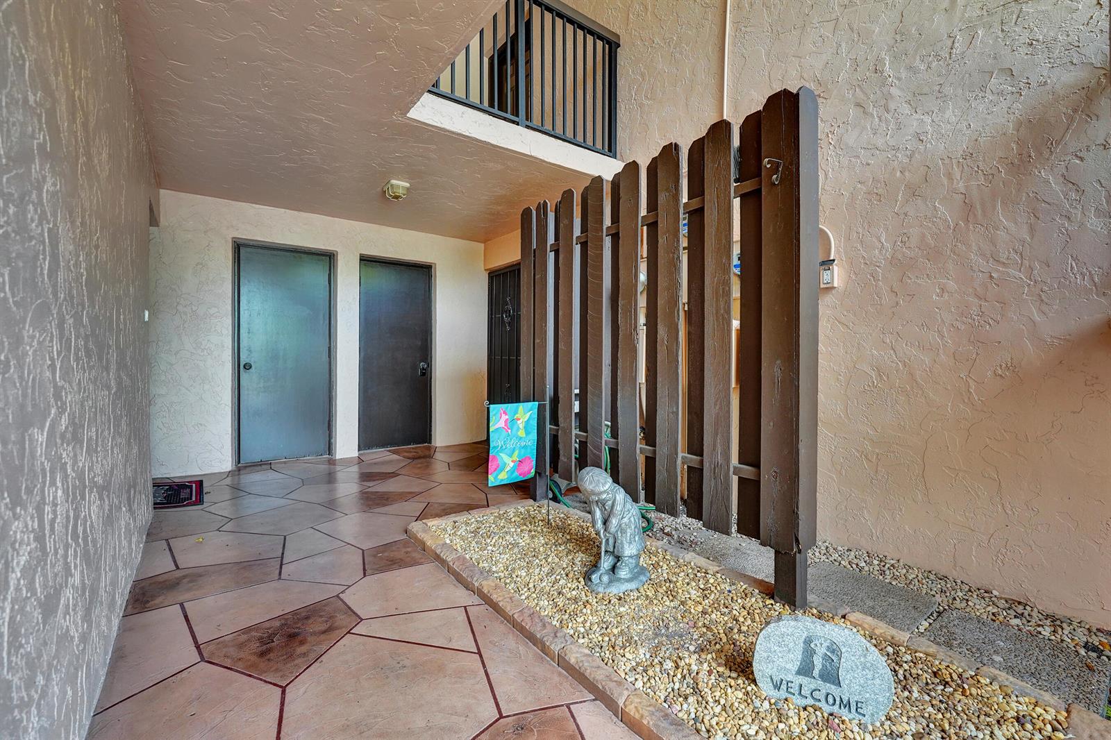 An outdoor entryway features a stone-tiled floor, a wooden privacy fence, and a gravel garden bed — 2160 SW 93 Way # 1002, Davie FL 33324, DAVIE, FL