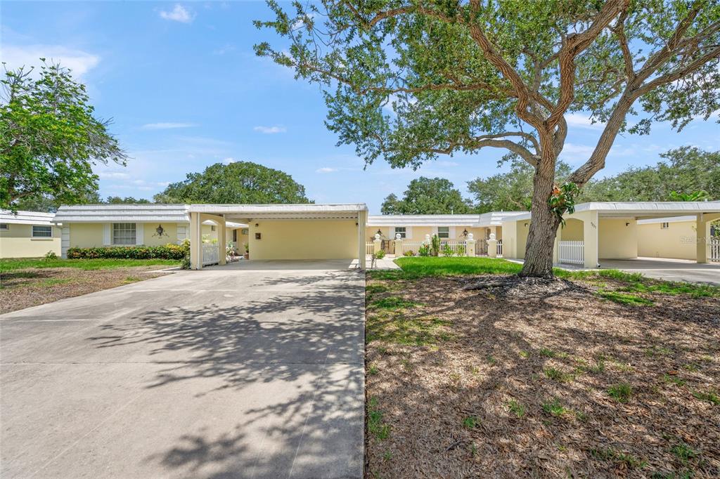 A single-story yellow house with a concrete driveway and a covered carport under a tree — 5823 TIDEWOOD AVENUE UNIT 19, SARASOTA, FL