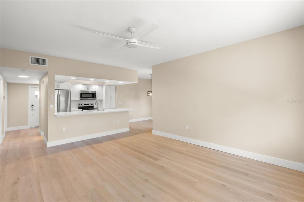 A bright, open-concept living area features light wood flooring, a ceiling fan, and a kitchen — 5823 TIDEWOOD AVENUE UNIT 19, SARASOTA, FL