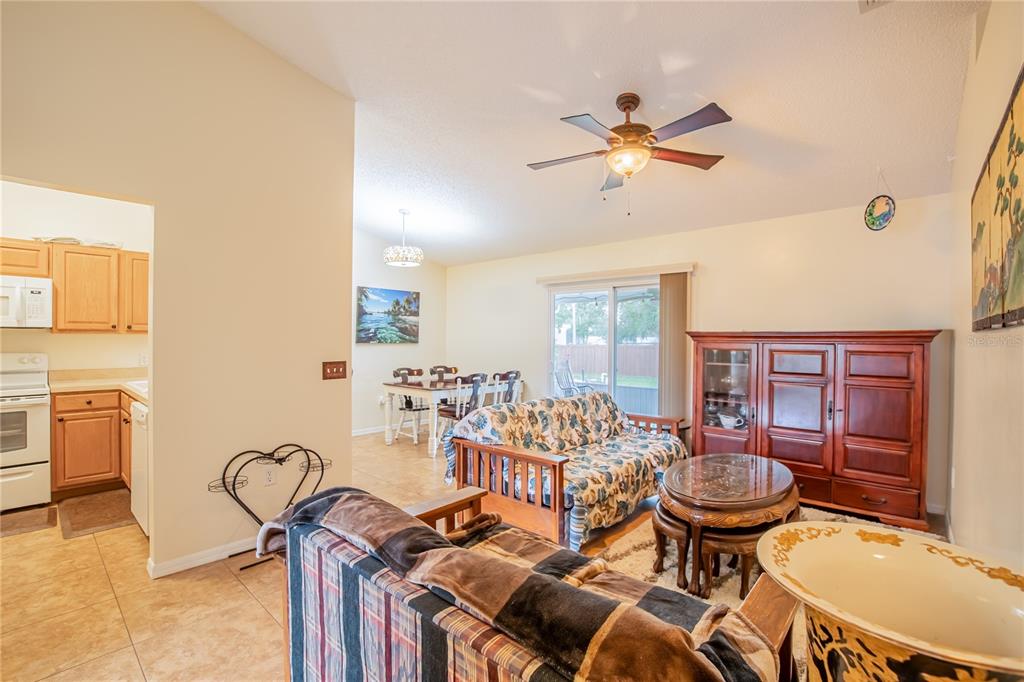 A kitchen with a breakfast bar, rattan stools, and light-colored cabinetry overlooks a living area — 7160 PEBBLE PASS LOOP, LAKELAND, FL