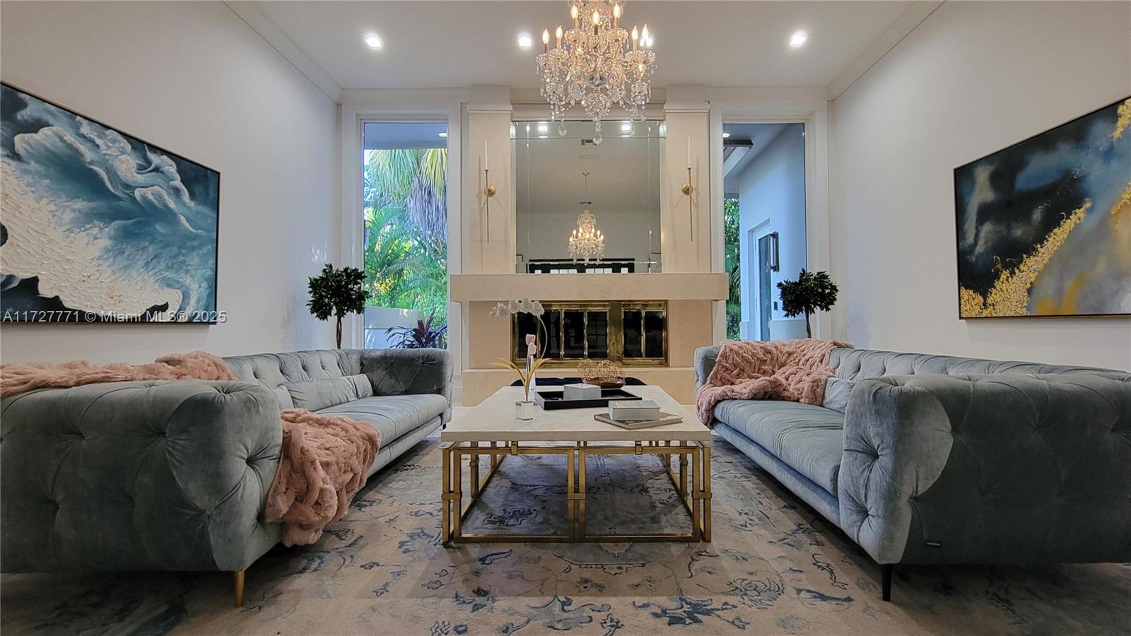 A formal living room features two velvet sofas, a central fireplace, and a crystal chandelier — 7700 S Woodridge Dr, Parkland FL 33067, PARKLAND, FL