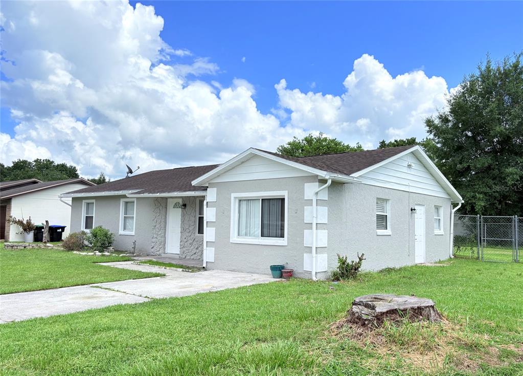 A single-story house with a gray stucco exterior, white trim, and a concrete driveway — 4428 CAROUSEL ROAD, ORLANDO, FL