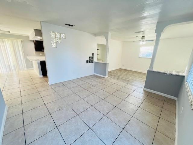 An open-concept room features light-colored floor tiles, a white wall with glass blocks, and wood-look flooring — 4428 CAROUSEL ROAD, ORLANDO, FL