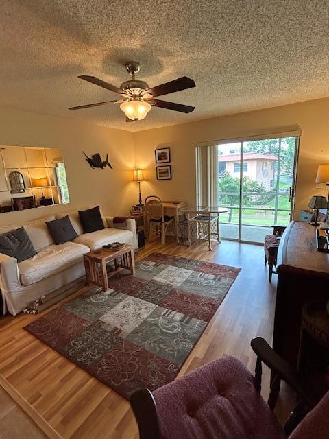 A living room features a ceiling fan, a patterned area rug, and a sliding glass door — 1951 SW Palm City Road # H, Stuart FL 34994, STUART, FL