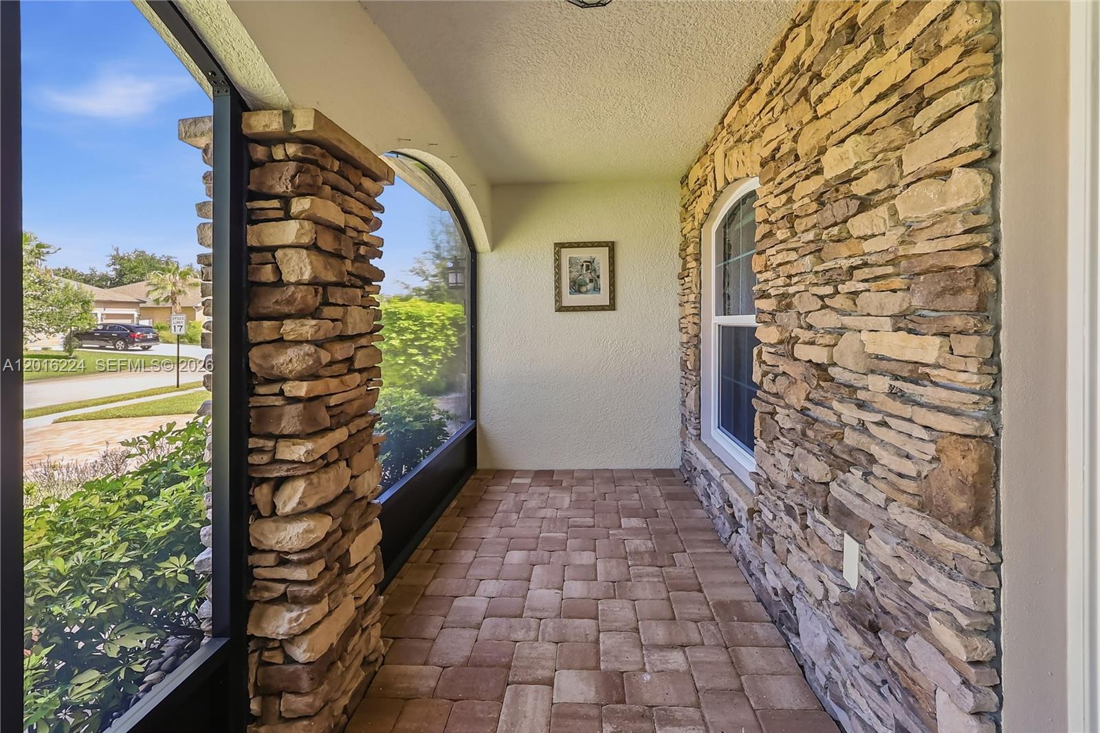 A covered porch features stone-clad pillars, a stone wall, and a brick paver floor — 4738 Ashley Lake Cir, Vero Beach FL 32967, VERO BEACH, FL