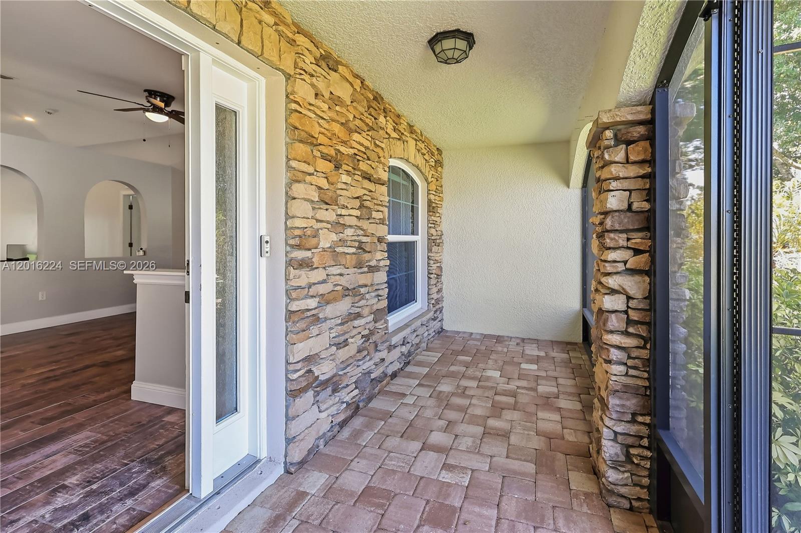 A covered patio features stone veneer walls, paver flooring, and a screened enclosure — 4738 Ashley Lake Cir, Vero Beach FL 32967, VERO BEACH, FL