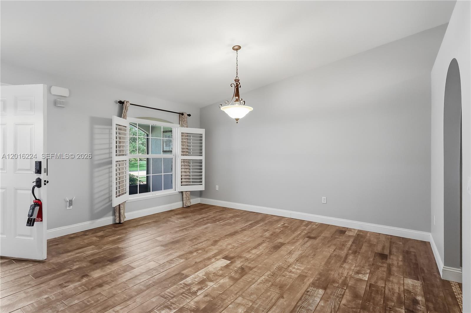 A dining room with light gray walls, wood-look flooring, and a central pendant light fixture — 4738 Ashley Lake Cir, Vero Beach FL 32967, VERO BEACH, FL