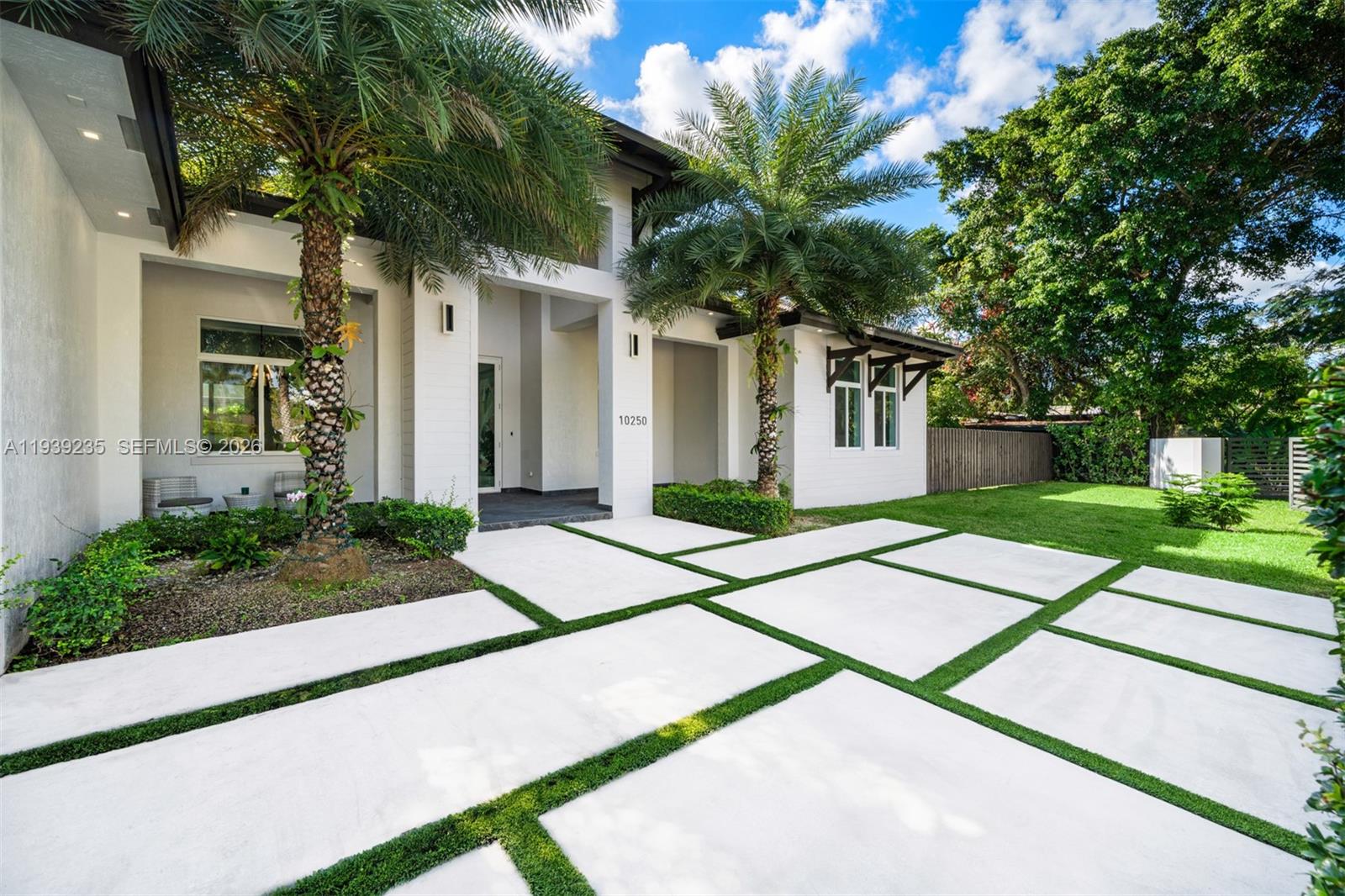 The exterior of a modern white house features a paved driveway with grass inlays — 10250 SW 135th St, Miami FL 33176, MIAMI, FL