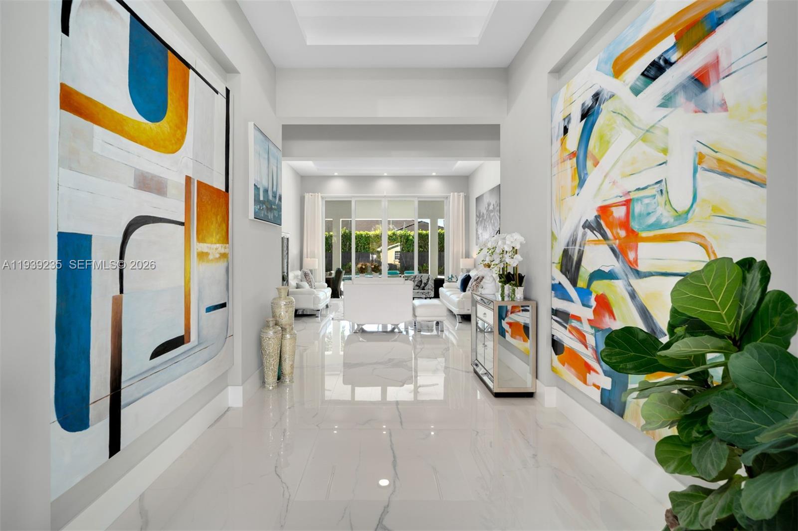 A bright hallway with large abstract paintings leads to a living area with glass doors — 10250 SW 135th St, Miami FL 33176, MIAMI, FL
