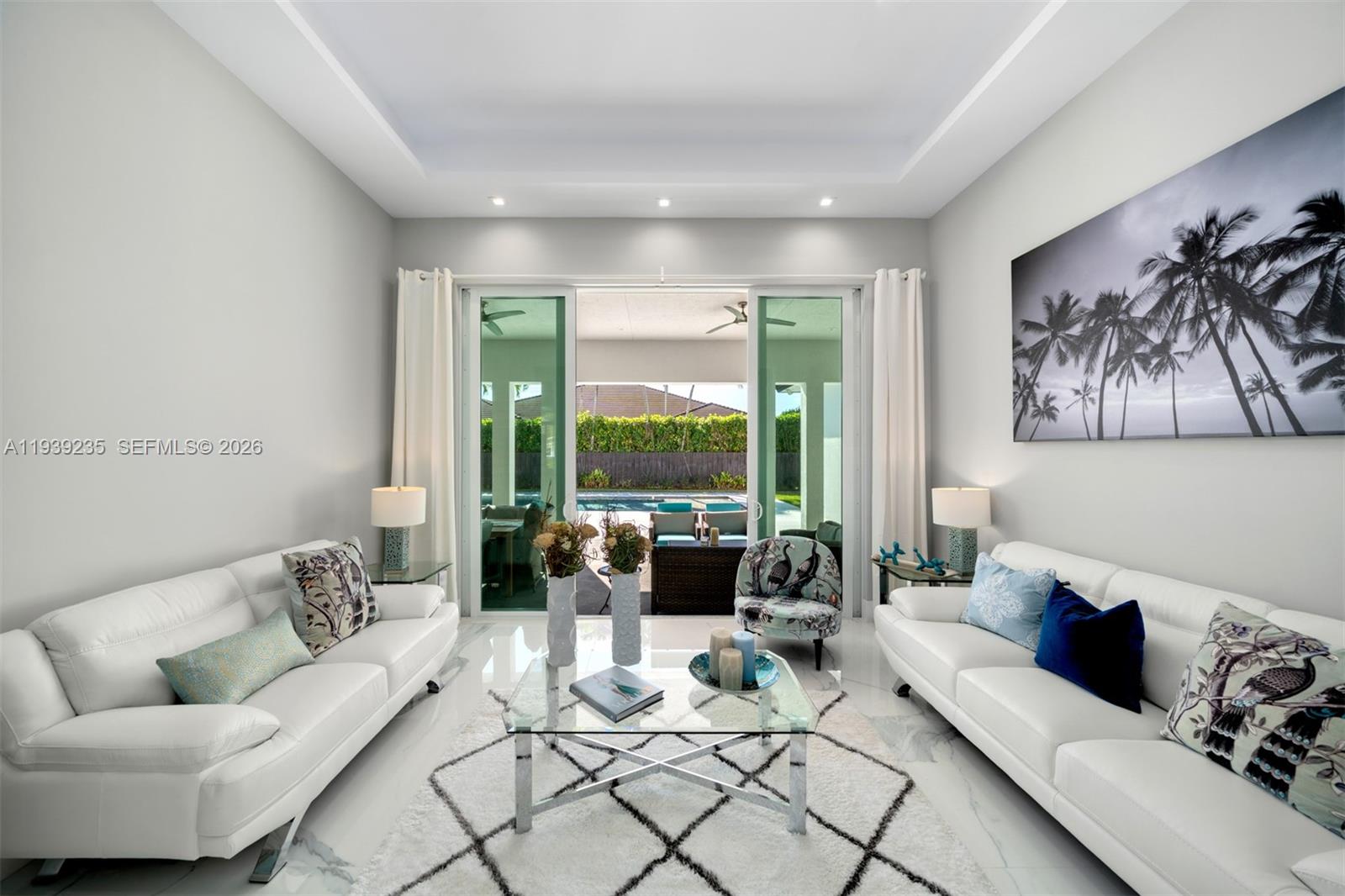 A bright living room features two white sofas, a glass coffee table, and sliding doors — 10250 SW 135th St, Miami FL 33176, MIAMI, FL