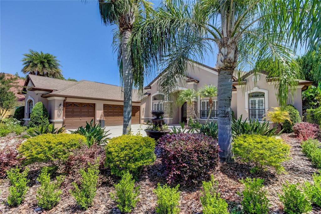 A single-story house with a three-car garage, palm trees, and a landscaped front yard — 1422 ARISTIDES COURT, ODESSA, FL