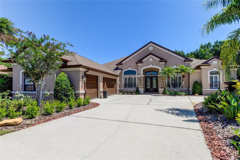 A single-story house with a beige stucco exterior, a concrete driveway, and a two-car garage — 1422 ARISTIDES COURT, ODESSA, FL