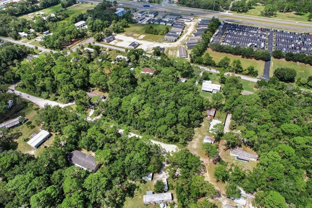 An aerial view shows a wooded lot surrounded by residential properties and a nearby highway — 1420 S HIGHCLIFF POINT, HOMOSASSA, FL
