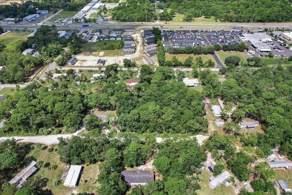 An aerial view shows a wooded residential area with scattered houses and a nearby parking lot — 1420 S HIGHCLIFF POINT, HOMOSASSA, FL