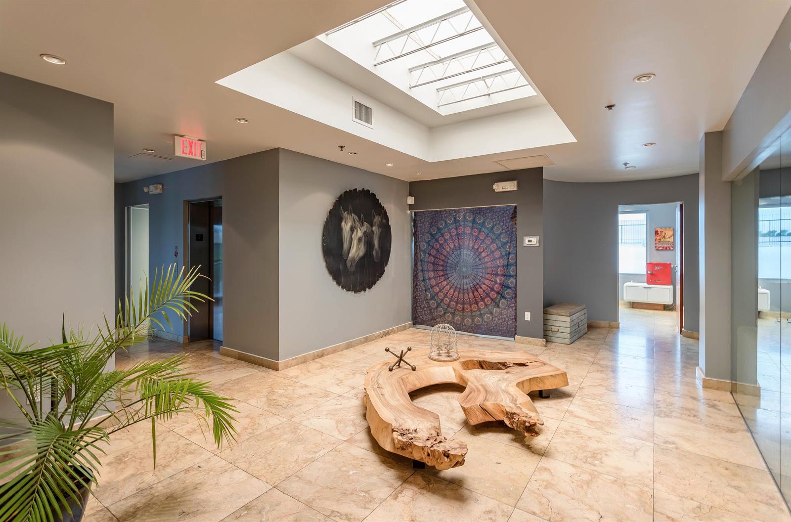 A lobby with a skylight, tile floors, a live-edge wood table, and decorative wall art — 5020 Biscayne Boulevard, Miami FL 33137, MIAMI, FL
