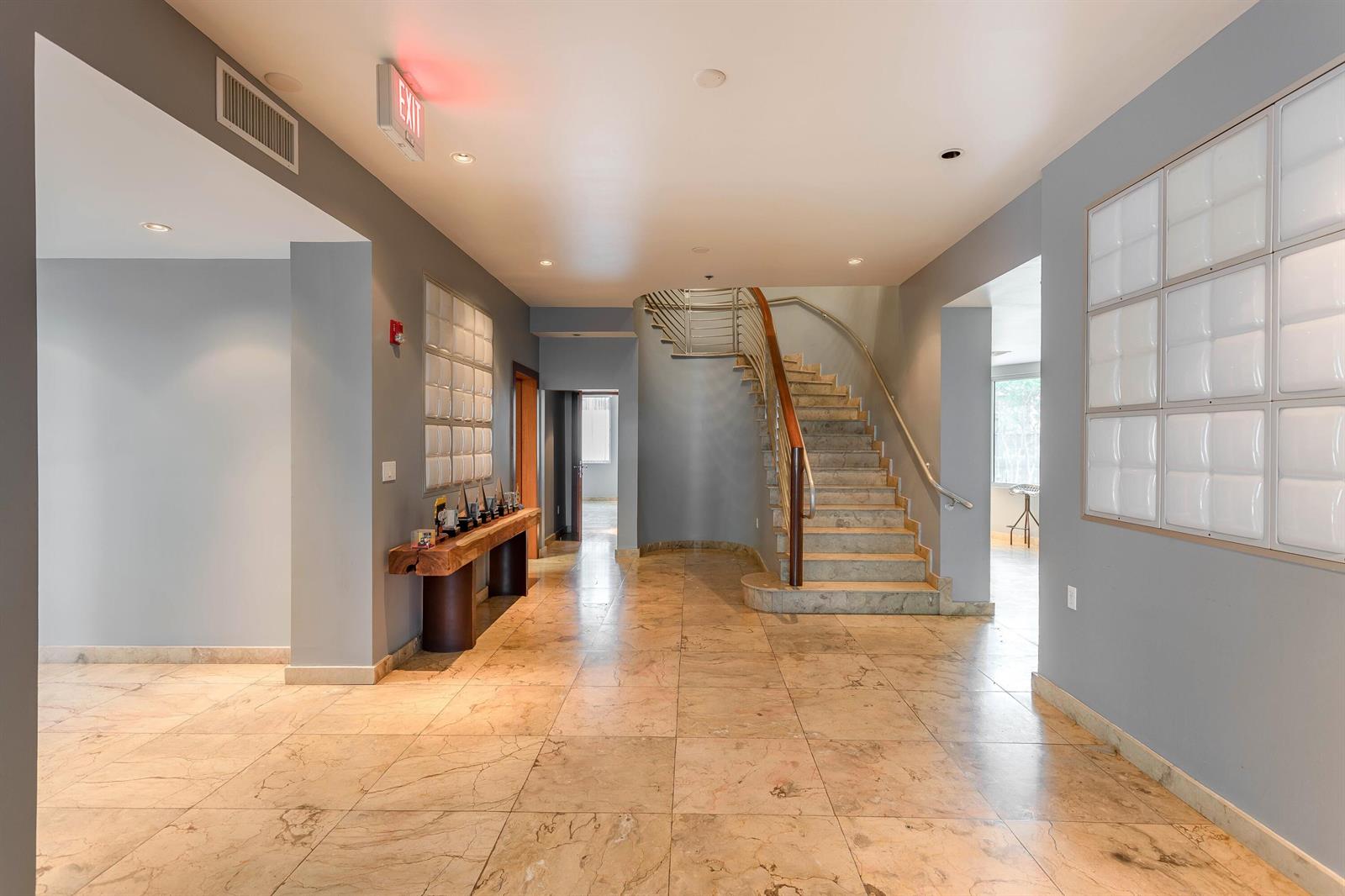 A spacious lobby features marble tile flooring, a central staircase, and gray walls — 5020 Biscayne Boulevard, Miami FL 33137, MIAMI, FL