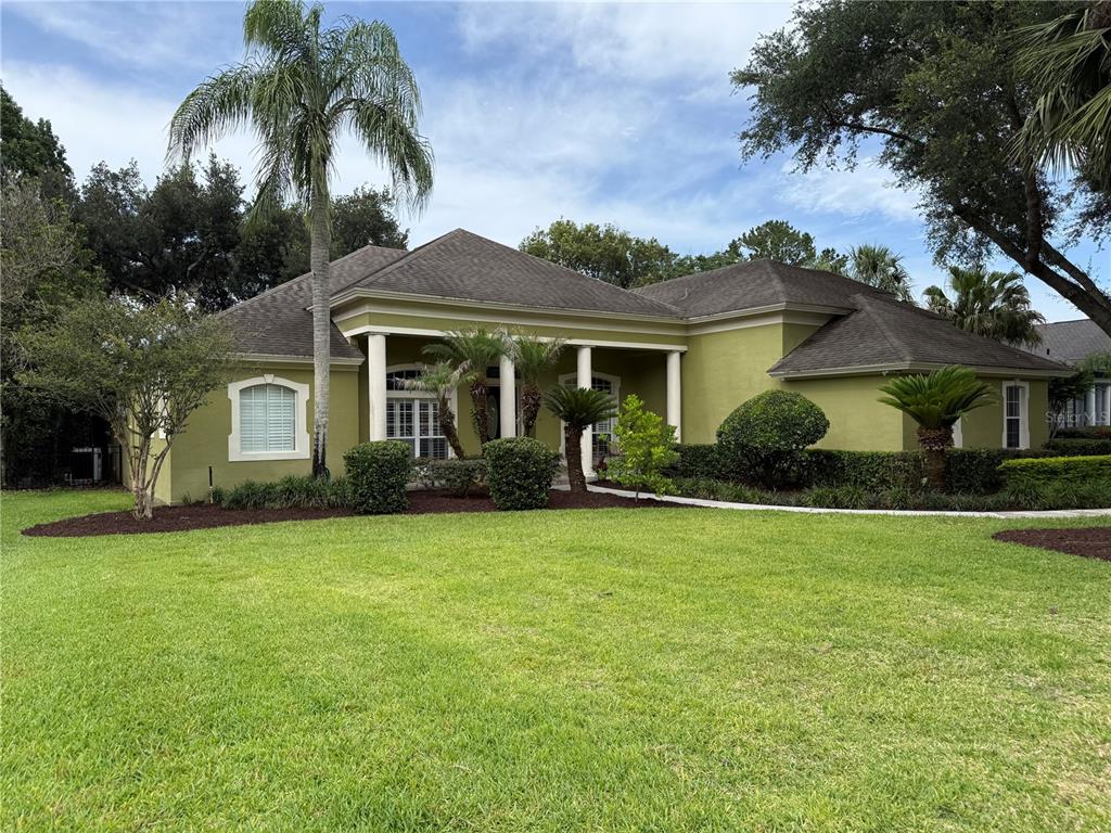 A single-story house with green stucco walls, a dark shingled roof, and a palm tree — 149 CHERRY CREEK CIRCLE, WINTER SPRINGS, FL
