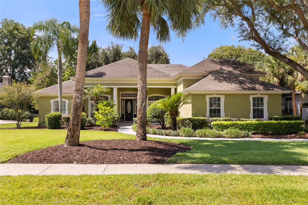 A single-story house with a green exterior, a covered entryway, and palm trees in the yard — 149 CHERRY CREEK CIRCLE, WINTER SPRINGS, FL