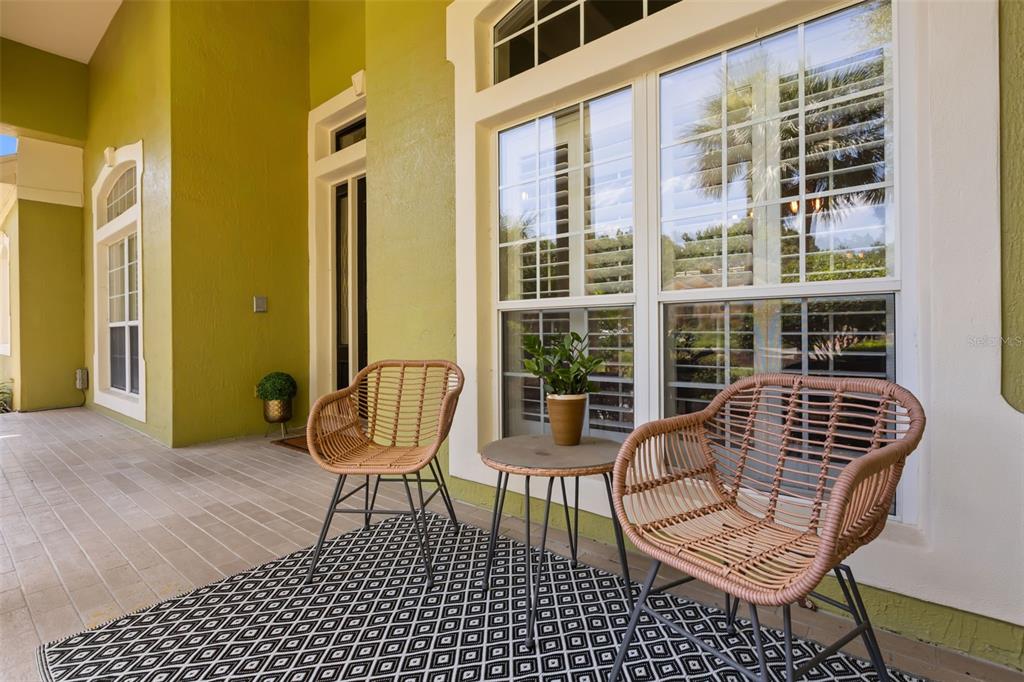 A covered patio features two wicker chairs, a small table, and a geometric patterned rug — 149 CHERRY CREEK CIRCLE, WINTER SPRINGS, FL