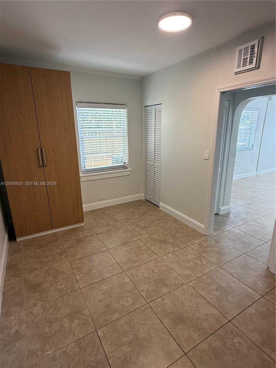 A room with light-colored tile flooring, a wooden wardrobe, and a doorway leading elsewhere — 2816 Pine Tree Dr # 2, Miami Beach FL 33140, MIAMI BEACH, FL