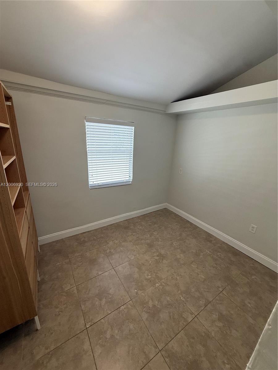 A small room features light-colored walls, tile flooring, a window with blinds, and shelving — 2816 Pine Tree Dr # 2, Miami Beach FL 33140, MIAMI BEACH, FL